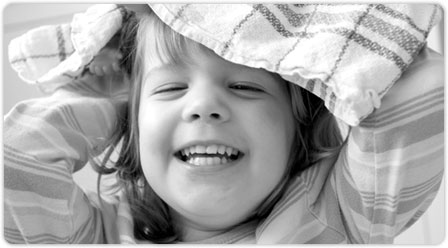 Young child laughing and playing with tea towel